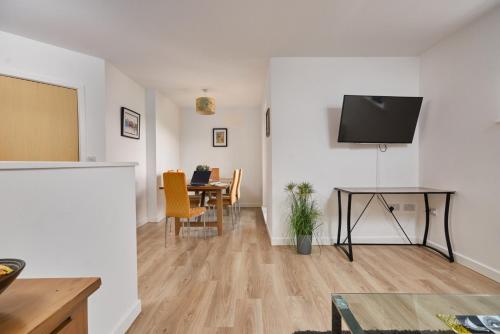 a living room with a table and a tv on a wall at Wilford View in Nottingham