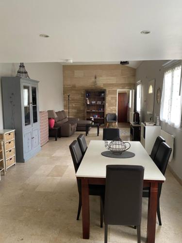 a dining room with a table and chairs and a living room at L'Araucaria in Pontault-Combault