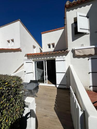 Cette maison blanche dispose d'une terrasse couverte et d'un balcon. dans l'établissement Studio à côté de la plage, au Cap d'Agde
