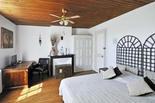a bedroom with a bed and a desk and a ceiling fan at Périgord Escapades in Pineuilh