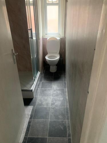 a small bathroom with a toilet and a window at The New Macleods Guest House in Blackpool