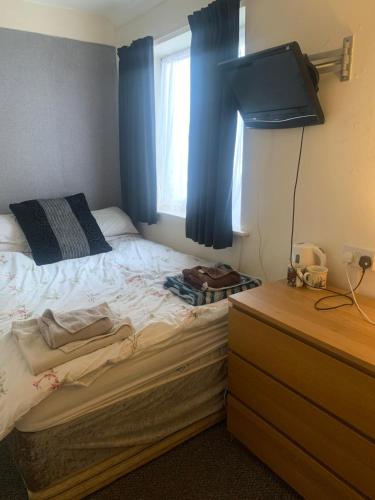 a bedroom with a bed with blue curtains and a dresser at The New Macleods Guest House in Blackpool