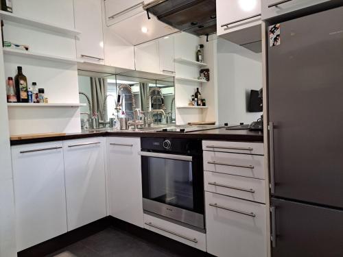 eine Küche mit weißen Schränken und einem schwarzen Backofen in der Unterkunft Hameau du Puech, rez-de-jardin avec parking et clim in Cap d'Agde