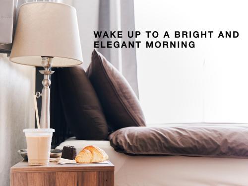 a lamp on a table next to a bed with a cup of coffee at Evergreen Apartment Hotel in Tokyo