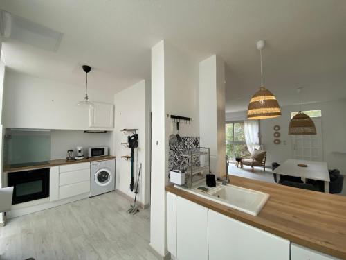 une cuisine blanche avec un évier et un micro-ondes dans l'établissement Duplex 3 Chambres Proche Gare Clim, WIFI, parking, à Perpignan