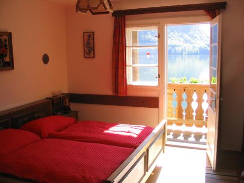 a bedroom with a red bed and a window at Pension Sarstein in Hallstatt