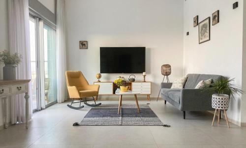 a living room with a couch and a tv at Your Perfect Place by the Mediterranean in H̱adera