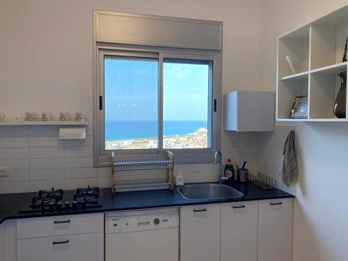 a kitchen with a sink and a window at Your Perfect Place by the Mediterranean in H̱adera