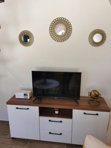 a tv on a white cabinet with a clock on the wall at Tara 1395 Altitude in Sekulić 