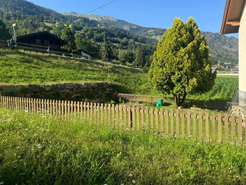 a wooden fence with a tree in a field at Ferienwohnung Die Möll in Latzendorf