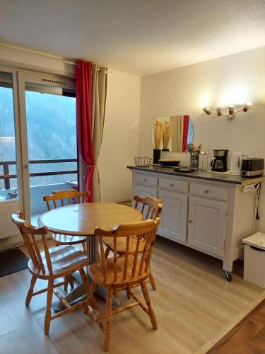 une cuisine avec une table, des chaises, une table et un comptoir dans l'établissement Appartement calme et apaisant, à Saint-Jean-dʼAulps