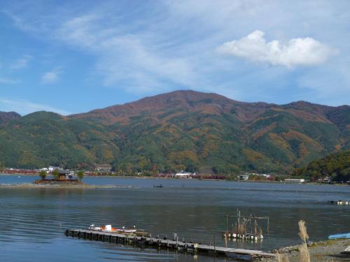 a dock in the middle of a lake with mountains at Lakeland Hotel Mizunosato in Fujikawaguchiko