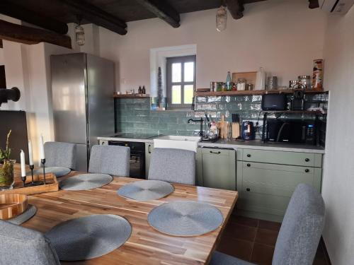 a kitchen with a wooden table with chairs and a counter at RIGLI vendégház in Závod