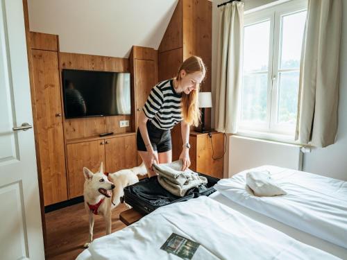 a woman standing in a bedroom with a dog standing next to a bed at Ferienhaus in Schierke mit Garten in Schierke