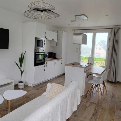 Il comprend un salon blanc avec un canapé et une cuisine. dans l'établissement petite maison 3km de la mer, à Ozeville