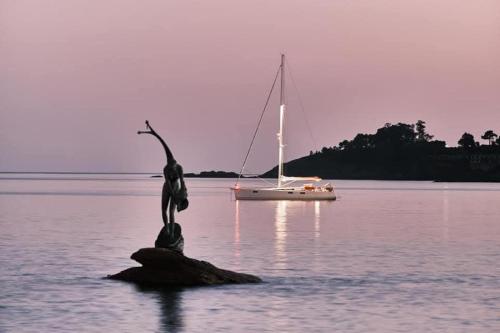 a statue on a rock in the water with a sailboat at VUT "O Pazo" Sanxenxo os espera in Sanxenxo