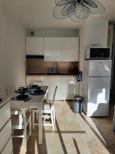 une cuisine avec une table et un réfrigérateur blanc dans l'établissement Cassis 4 pers Vue Mer Wifi Piscine Parking Tennis, à Cassis