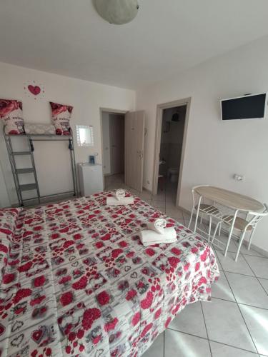 a bedroom with a bed with a red and white quilt at B&B Metalla in Iglesias