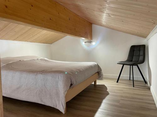 a bedroom with a bed and a black chair at La Maison de Georgette in Versols-et-Lapeyre