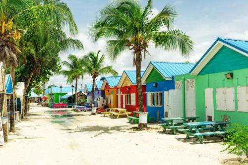a row of colorful houses on a beach with palm trees at Mango Tree House in Christ Church
