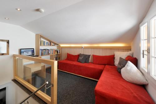 a living room with a red couch and a book shelf at Alpinhotel Bort in Grindelwald