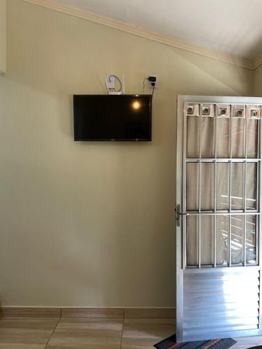 a room with a tv on the wall and a door at Chalé Roda Dágua A in Alto Caparao