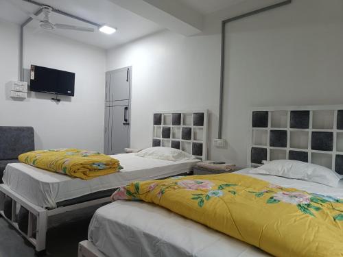 a bedroom with two beds and a tv on the wall at Jiya Mansion Guest house, Homestay in Guwahati