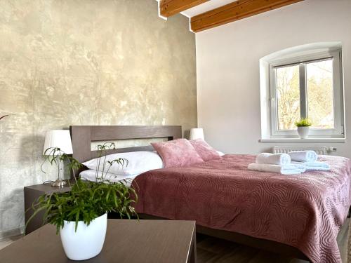 a bedroom with a bed with pink sheets and a window at Penzion Sen in Černá v Pošumaví