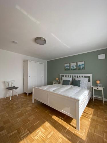 a bedroom with a large white bed and a wooden floor at Apartment Wolkenblick in Leutkirch im Allgäu