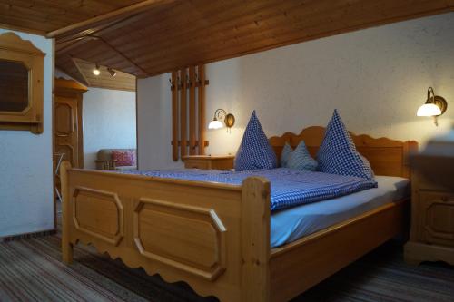 um quarto com uma grande cama de madeira com almofadas azuis em Gästehaus Wagner em Egglfing