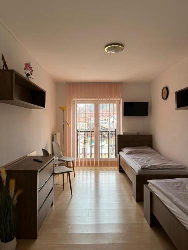 a room with two beds and a chair and a window at Penzión Centrum in Terchová