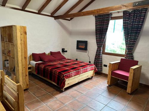 a bedroom with a bed with red pillows and a window at Casa Rural Ruta del Tajinaste azul in Valsequillo