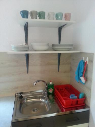 a kitchen sink with plates and bowls on shelves at Domki w Zacisznej Zagrodzie in Jerzykowice