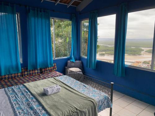 a bedroom with blue walls and a bed with blue curtains at Banana Leaf Eco Hostel in Barra de Guaratiba