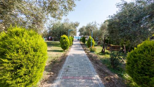 a path through a garden with bushes and trees at Concept Bungalow in Ayvacık