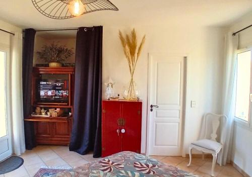 a bedroom with a red cabinet and a mirror at La petite maison de Valérie proche château de la Rode, du Domaine de Flore et du Lac Saint Ferréol in Lempaut
