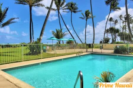 a swimming pool with palm trees in the background at Amazing 7th floor Beachfront Condo in Hauula