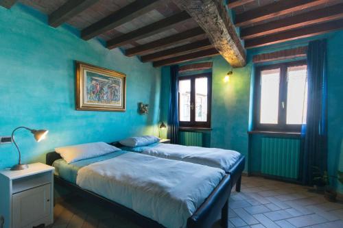 two beds in a room with blue walls and windows at Villa Gaia in Santa Maria della Versa