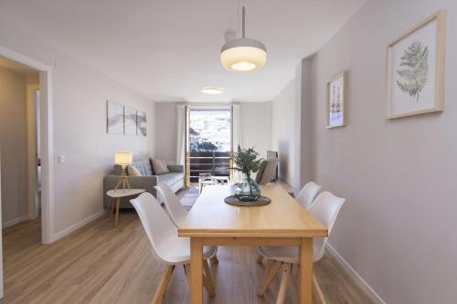 Un comedor con una mesa y sillas blancas. en La Ventana de Formigal by BeValle, en Formigal