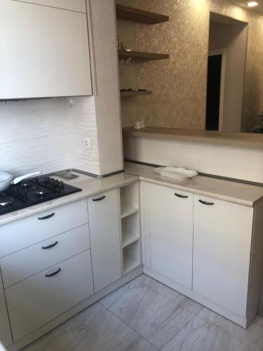 a kitchen with white cabinets and a stove at Tbilisi Sea Apartments in Tbilisi City
