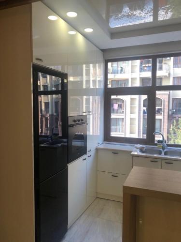 a kitchen with white cabinets and a black refrigerator at Tbilisi Sea Apartments in Tbilisi City
