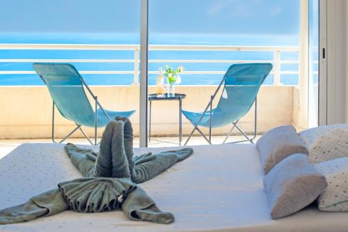 - une chambre avec deux chaises et un lit offrant une vue sur l'océan dans l'établissement VILLA FLORENTINE II - Somptueux deux pièces MONACO - Vue mer - Parking, à Beausoleil
