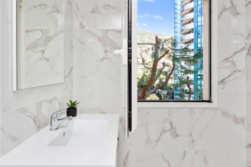 une salle de bain blanche avec un lavabo et une fenêtre dans l'établissement VILLA FLORENTINE II - Somptueux deux pièces MONACO - Vue mer - Parking, à Beausoleil