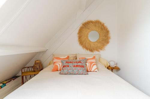 a white bed with pillows on it in a attic at La Cabine - cœur de Honfleur - vue imprenable in Honfleur