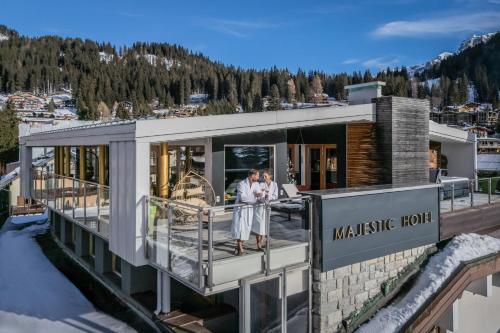 due persone in piedi sul balcone di una casa di Majestic Hotel a Madonna di Campiglio
