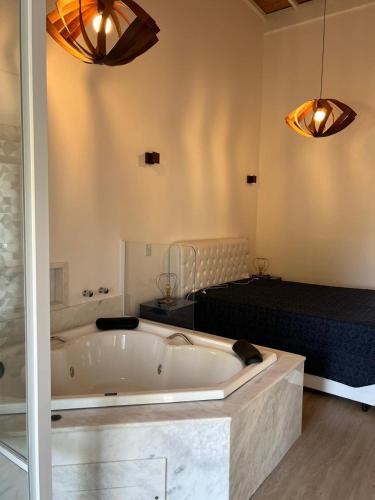 a white bath tub in a room with a bed at Chalé Centro de Monte Verde in Monte Verde