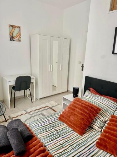 a bedroom with a bed with orange blankets and a desk at Le Shamma lodge in Reims