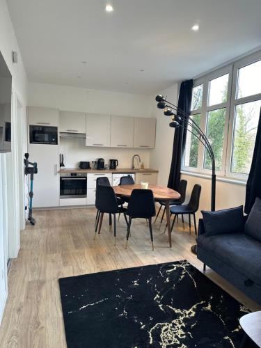 a living room with a table and chairs and a kitchen at Maison de l'Aar Appartement le Diamant luxueux et neuf 2 chambres Grand Salon Séjour in Strasbourg