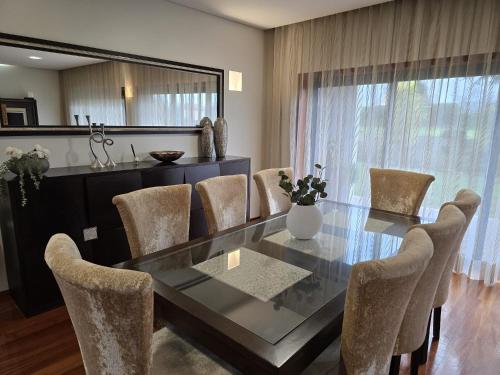 a dining room with a glass table and chairs at Petit Maison in Além da Ribeira
