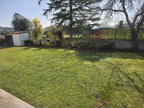 a yard with a large lawn with a fence at Petit Maison in Além da Ribeira
